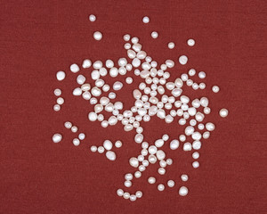 Beads of natural white freshwater pearl on red fabric background