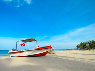 Rescue Fishing Boat on the beautiful white sand sandy beach with coconut trees and blue sky with clouds in background