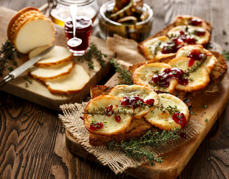Grilled sandwich  with smoked sheep cheese, thyme  and wild red huckleberry jam on a wooden rustic table