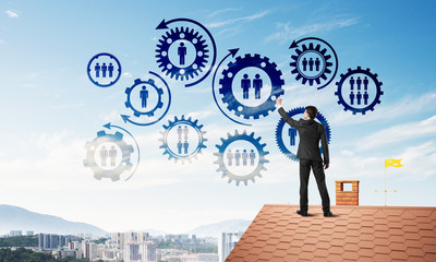 Businessman on house roof presenting teamwork and connection concept. Mixed media
