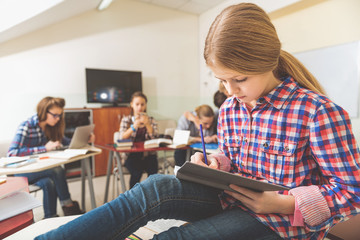 Fototapeta premium Young female pupil stubbornly writing