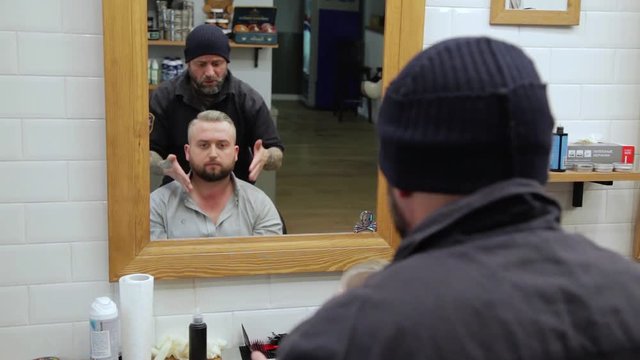 Barber cuts the hair of the client with clipper at barbershop.