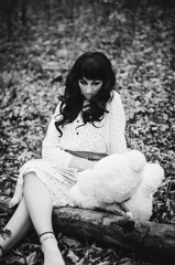 Young sad lonely brunette girl at sleepwear sitting on autumn fo