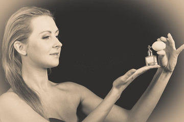 Beautiful woman with holding and applying perfume