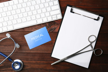 Keyboard, medical supplies and clipboard on wooden background
