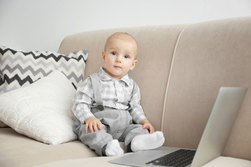 Fototapeta premium Cute baby boy with laptop on couch