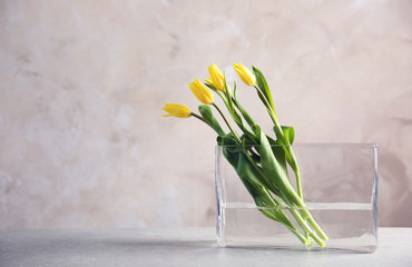 Glass vase with bouquet of beautiful tulips on color background