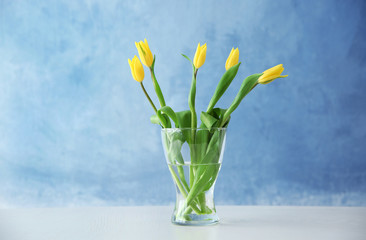 Glass vase with bouquet of beautiful tulips on color background