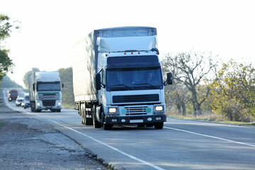 Big trucks on asphalt road in sunny day