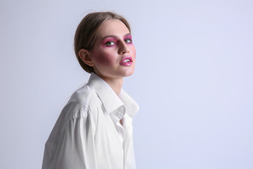 Young model with bright makeup on light background