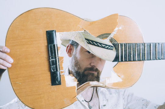 Cowboy touching the acoustic torn guitar