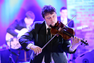 Young elegant man violinist plays the violin on a concert venue background showing emotions and face expressions.Lifestyle,music passion,music concert/Close-up of a musician playing his violin
