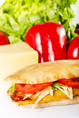 Fasting sandwich - Ciabatta with breaded peppers, tomatoes and vegetable cheese next to the fresh ingredients.