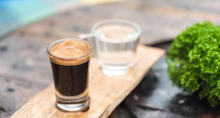 Espresso coffee cup serve with glass of water on wooden table