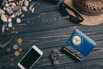 Travel background. Men's style clock, flashlight, documents, hat, compass, money, phone and camera on a wooden background