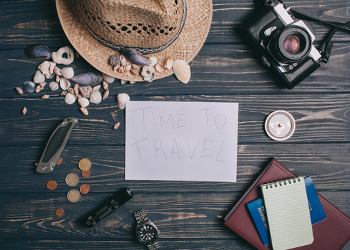 Travel background. Men's style clock, flashlight, documents, hat, compass, money, phone and camera on a wooden background