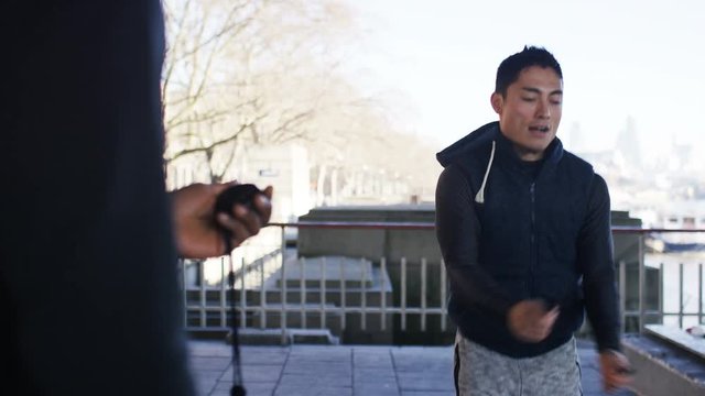 4K Personal trainer timing a man skipping with a jump rope, in slow motion