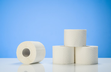 Toilet paper isolated on white table with blue background. Cleaning concept product photograph for advertising.