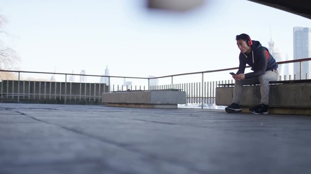 4K Male sitting down listening to music through his phone, in slow motion