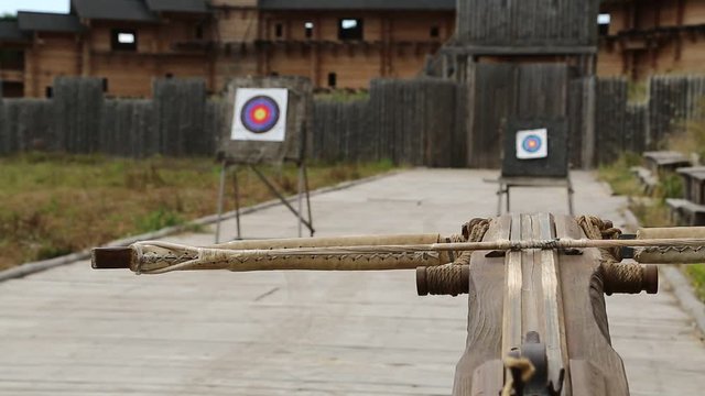 Crossbow is aimed at a target. Old wooden arbalest and targets at background. Ancient ballista
