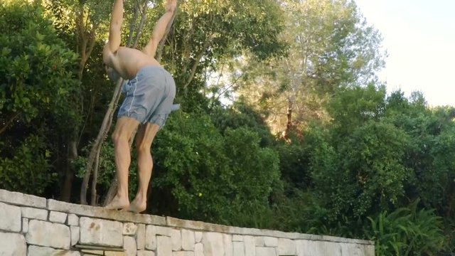 Young man performing backflip stunt on swimming pool