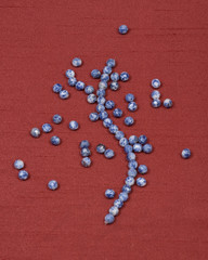 Round faceted sodalite beads and string on red fabric background