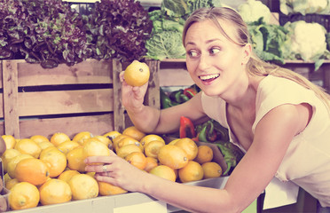 Obraz premium friendly woman holding lemons in hands in fruit store