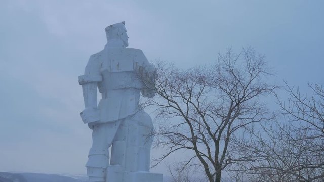 the Monument to Artyom, Made of White Granite Cubism Style , and a View on Christian Wooden Churches Called as Sviatogorskaya Lavra in Snowy Winter
