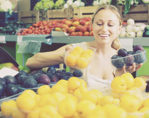 young woman buying plums at market.
