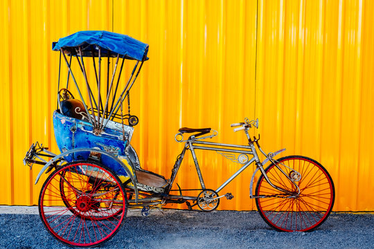 Old thai Cycle rickshaw/ Trishaws against yellow wall on background. colorful and useful for travel concept.