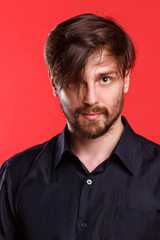 Man on a red background. Hipster in black shirt. Hairstyles with bangs.