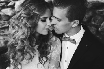 Fashion portrait of bride and groom close-up. Stylish dress and curly hair