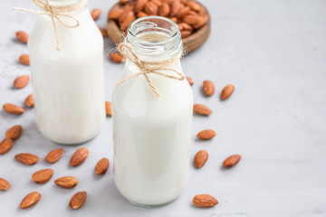 Almond milk in glass bottles with almonds on background, horizontal, copy space
