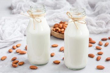 Almond milk in glass bottles with almonds on background, horizontal