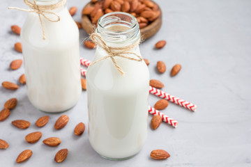 Almond milk in glass bottles with almonds on background, horizontal, copy space