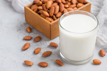 Almond milk in glass with almonds on background, horizontal, copy space