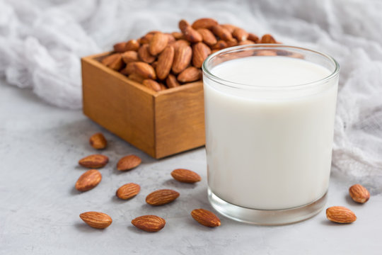 Almond milk in glass with almonds on background, horizontal, copy space