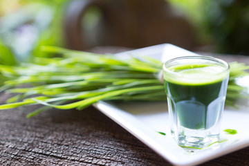 Green organic wheat grass drink over white wood background,top v