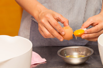 Obraz na płótnie Canvas Hands holding egg shell with egg yolk separated