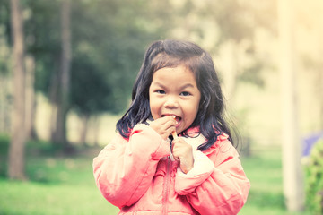 Cute asian little girl is eating ice-cream in the park 