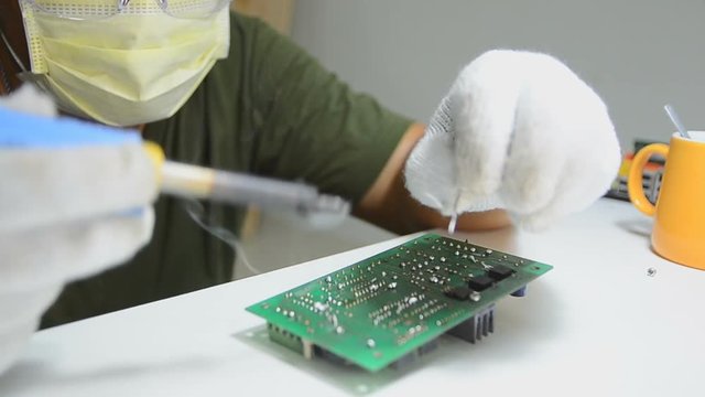 Technician is soldering to the electronic print circuit board