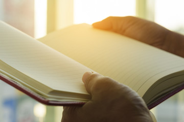 Hand holding book in the glass room