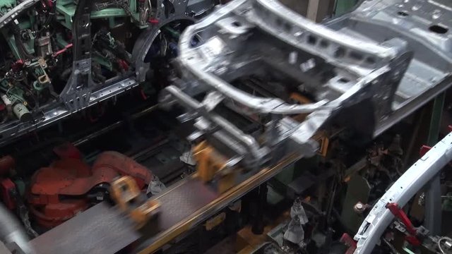 Car factory. Robotic arm machine welding and joining pieces. Making car in working lines