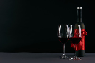 Wine bottle and two wineglasses on a dark background. Love card concept with copy space, Valentine's day theme