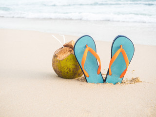 Colorful flip flops and coconut on the sandy beach