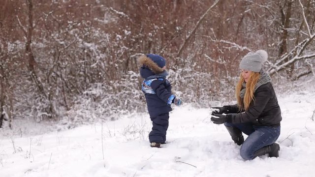 A young mother with a child having fun in a snowy forest.