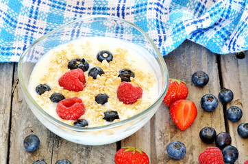 White yogurt in a bowl with oatmeal, blueberries, raspberries and strawberries