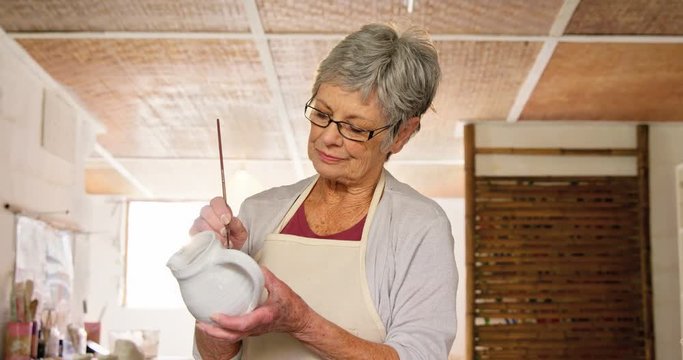 Female potter painting a jug