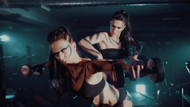 Two young muscular athletes in sportswear training with weights.
