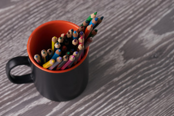 Colorful pencils in a cup on wooden table
